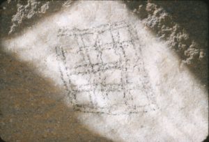 This design is located on the neck (below the chin) of the Peca Gasha. It is made up of sixteen squares in a 4 x 4 pattern. The checkerboard may represent two dimensional space. It appears to have been made by drilling the stone to obtain holes whose angle determines the shadows that make up the figure. Viewing the checkerboard is highly dependent on the time of the day, morning being best in the dry months of winter. Although eroded by the elements the design has survived. Nothing similar has been found elsewhere on the plateau.