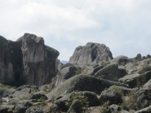 El Cerro de las Miradas, una roca enorme que se parece a un buque, situado en la parte sur de la meseta cercano a la Fortaleza y la laguna CachuCachu (Tabla 1). Fue nombrado tal porque en el convergen tres lineas de mira : el hombre de las Figuras 13a y 13b, una mujer al lado opuesto (Figura 13c), el cerro con el hombre y mujer apenas visibles a los costados en la parte posterior (Figura 13d) y la cabeza de un perro a la izquierda en Figura 13e. Fotos de Agosto 2003. 